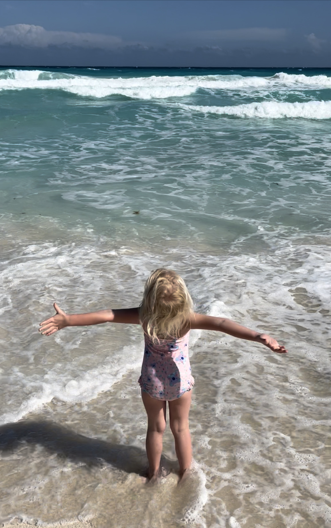 Little girl with arms outstretched embraces life on the beach